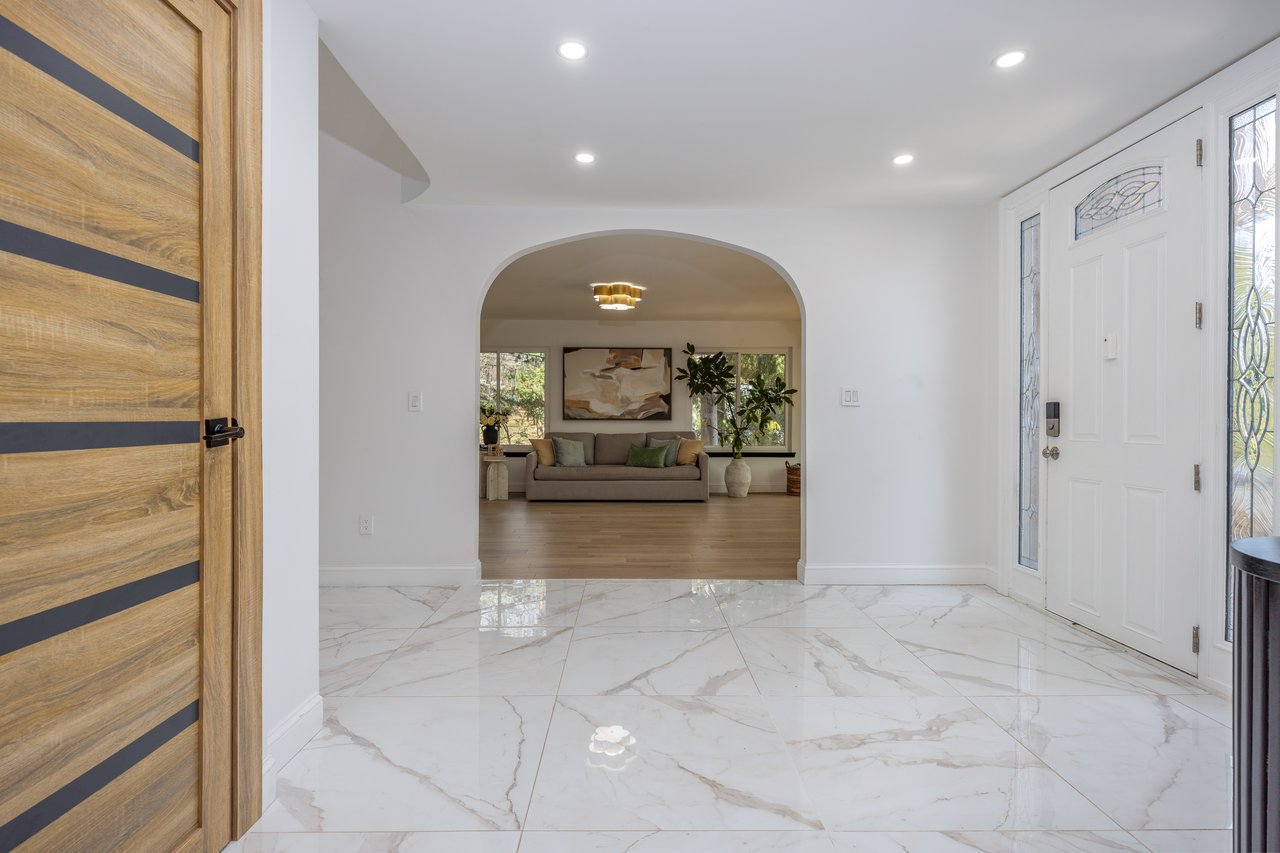 Entryway with light marble finish flooring, recessed lighting, and arched walkways...