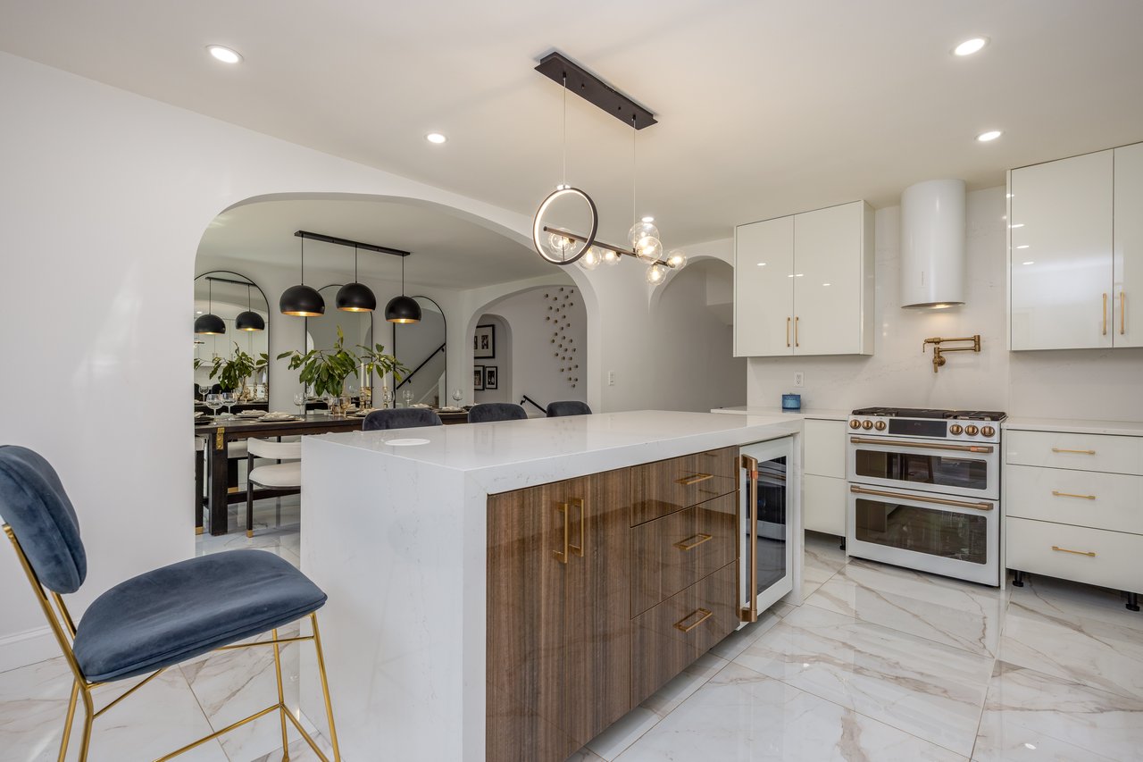 Kitchen with white cabinets, modern cabinets, double oven range, light stone counters, and decorative light fixtures