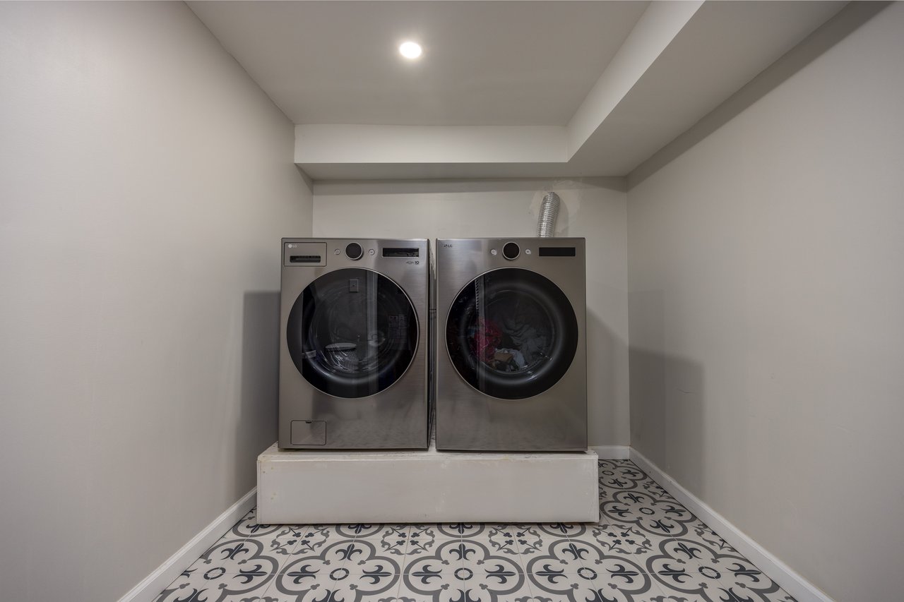 Washroom with tile patterned flooring and washing machine and clothes dryer