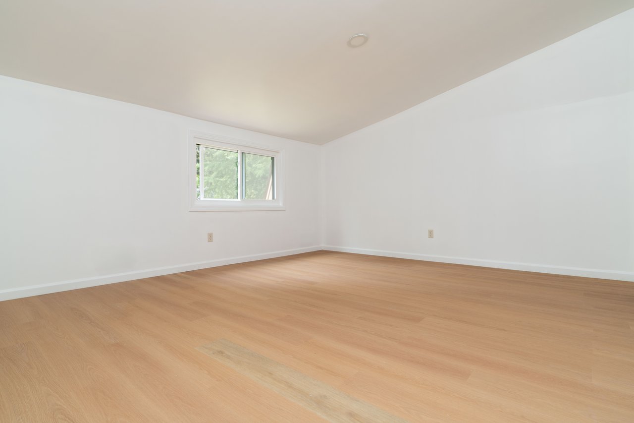 Empty room with light wood-style flooring and lofted ceiling