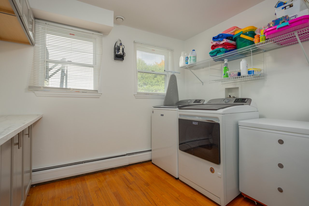 Laundry area featuring a baseboard radiator, light wood finished floors, and independent washer and dryer