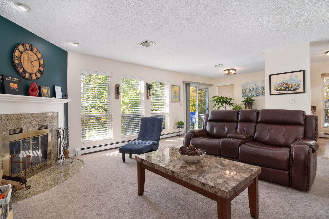 The living room flows seamlessly into the dining area, where floor-to-ceiling windows fill the space with natural light.