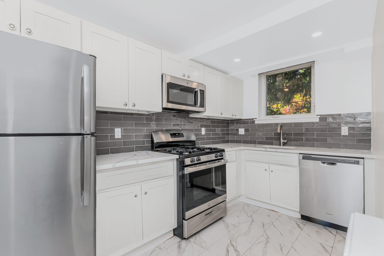 Kitchen featuring appliances with stainless steel finishes, tile backsplash, white cabinetry, quartz counter tops, tile flooring, and recessed lighting