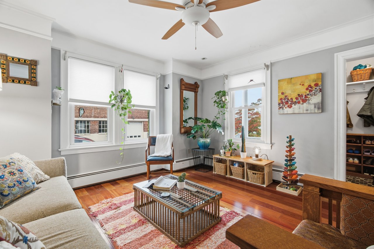 Living area featuring wood finished floors, ceiling fan, and baseboard heating