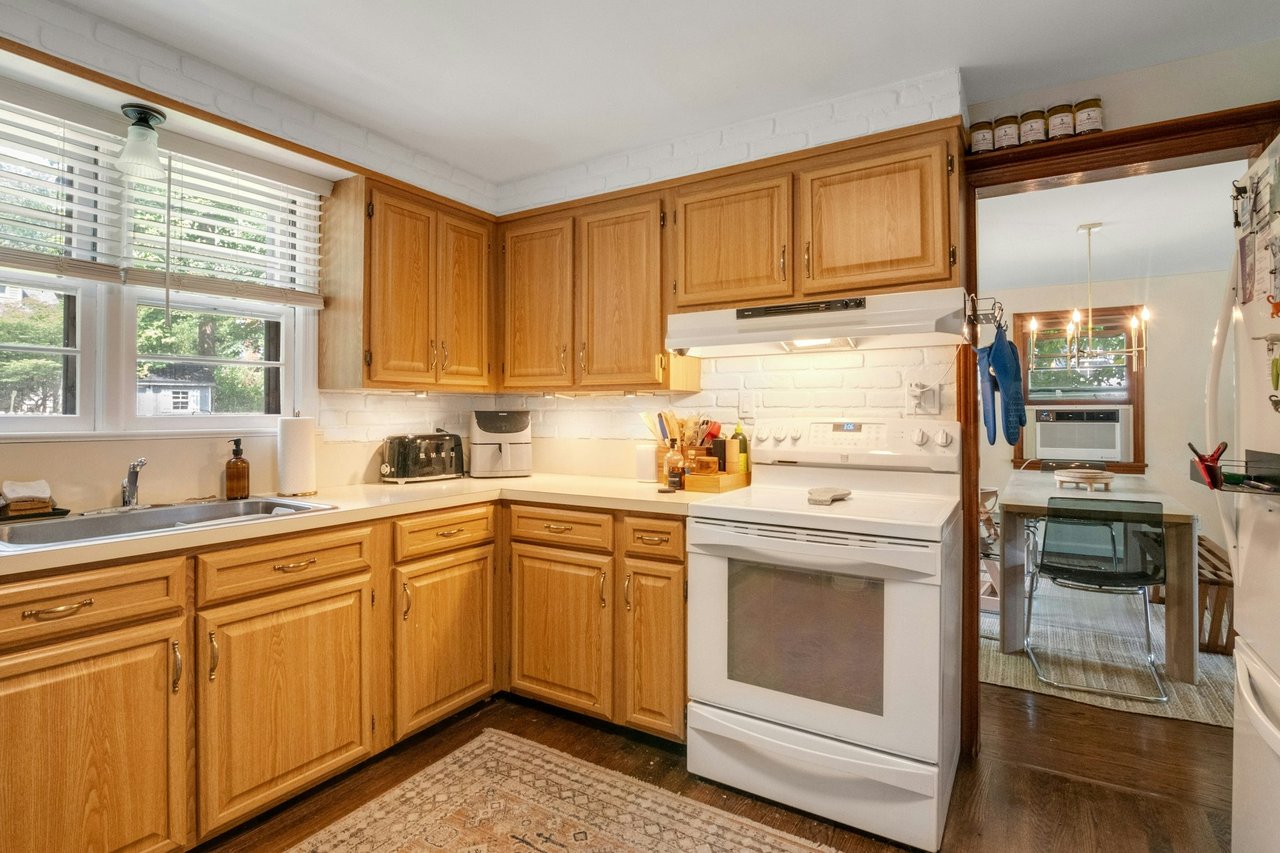 Kitchen with white appliances, light countertops, backsplash, dark wood-style floors, and under cabinet range hood
