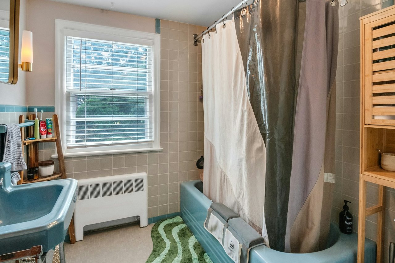 Bathroom featuring radiator heating unit, tile walls, and shower / bath combo
