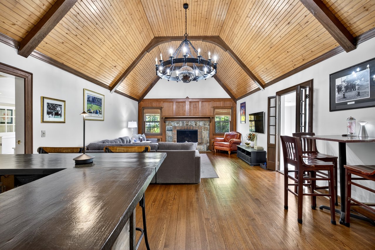 Living area featuring a chandelier, hardwood / wood-style flooring, high vaulted ceiling, a wood ceiling with exposed beams, and a brick fireplace