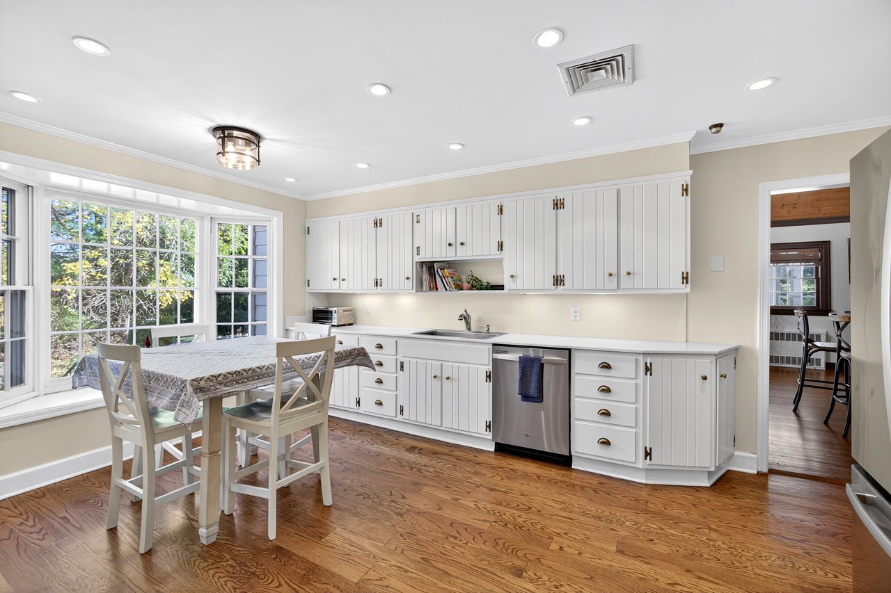 Kitchen with crown molding, light countertops, white cabinetry, light wood finished floors, and stainless steel appliances