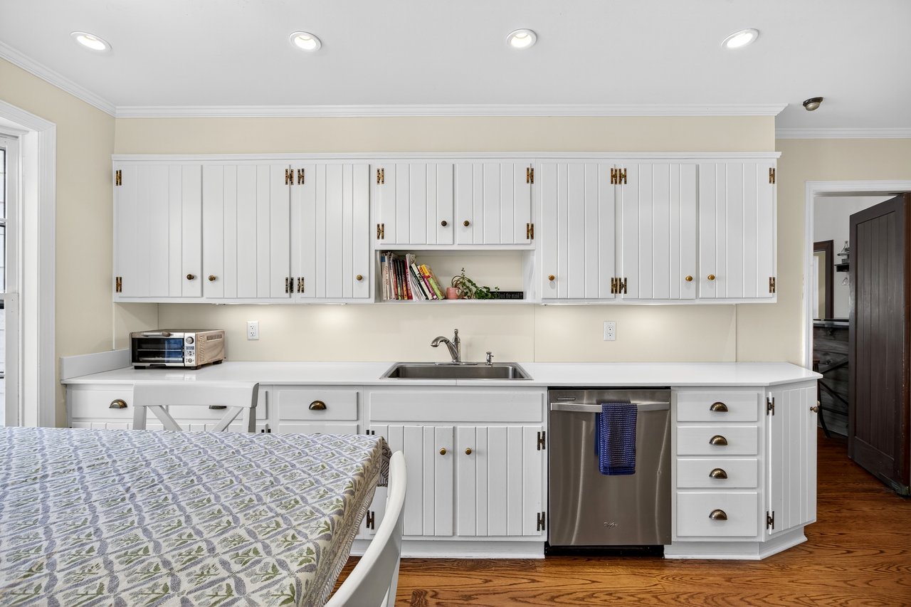 Kitchen featuring light countertops, ornamental molding, white cabinets, dishwasher, and open shelves