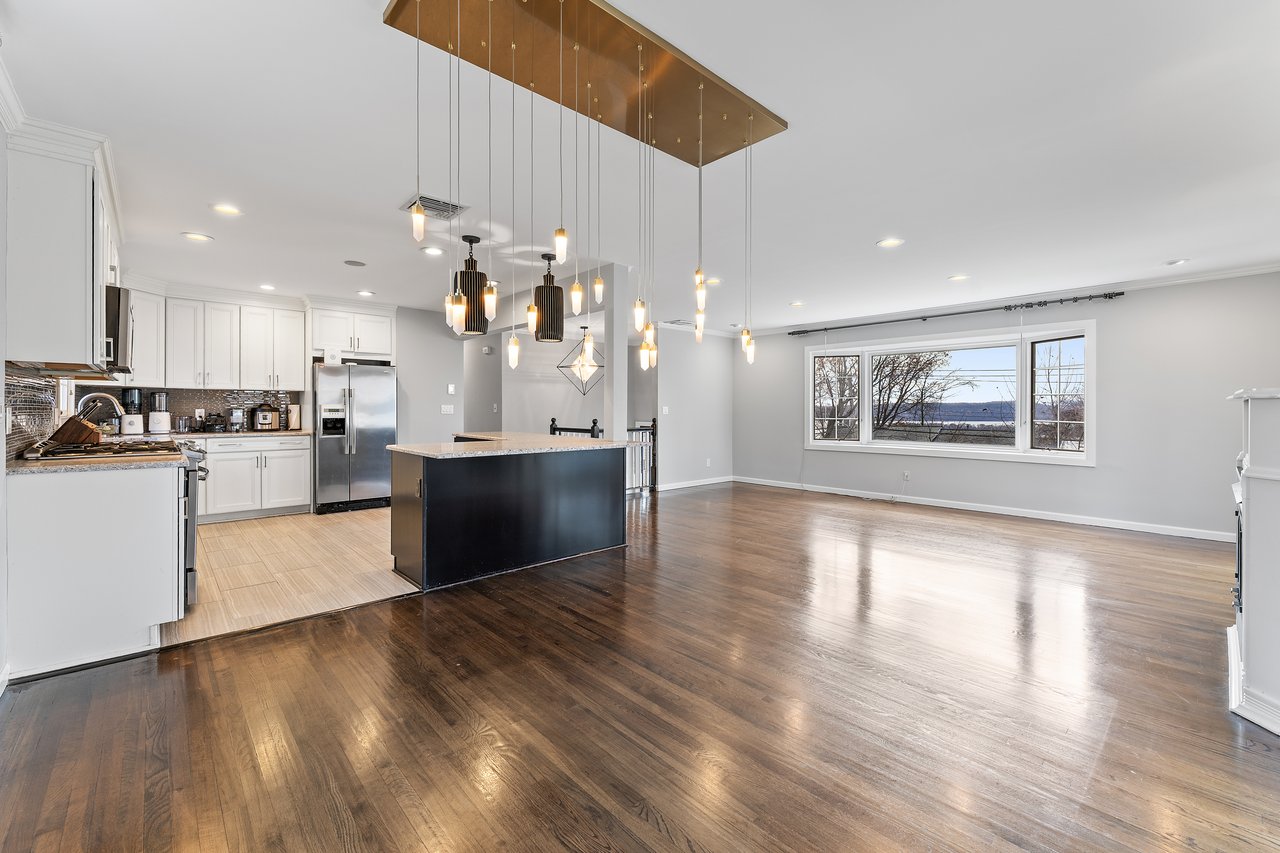 Kitchen featuring open floor plan, light wood-style floors, white cabinetry, decorative light fixtures, and a kitchen island