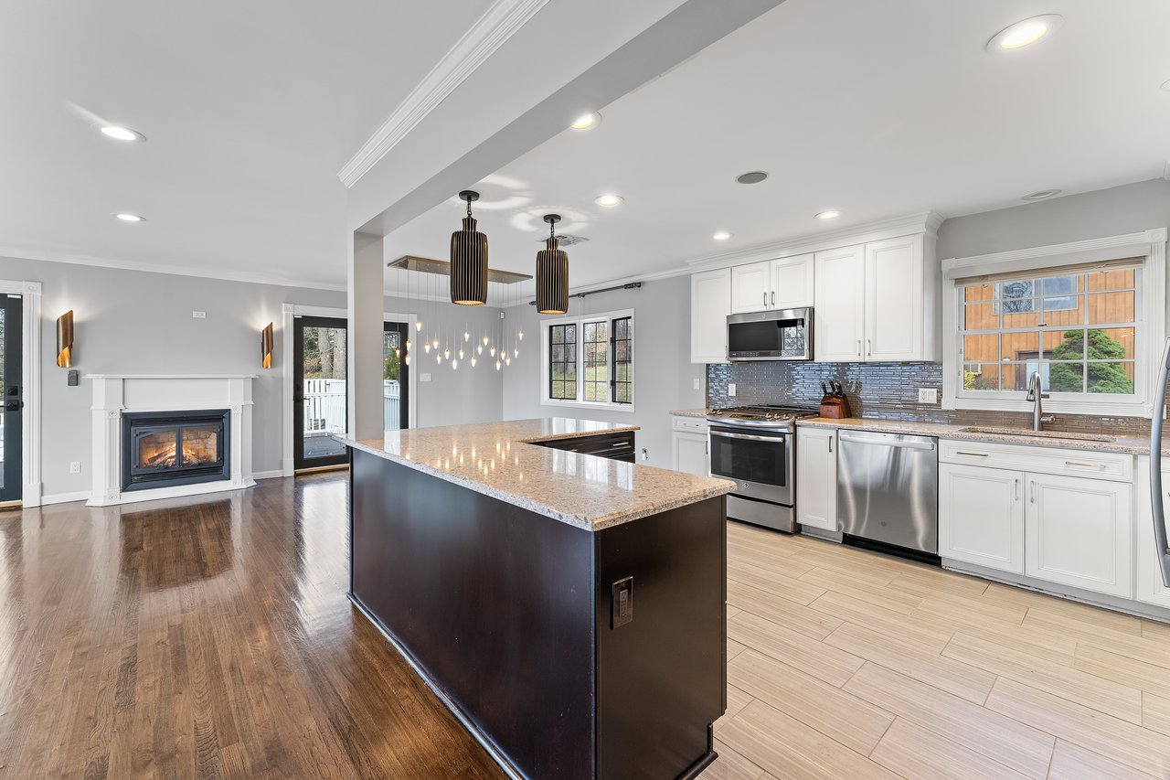 Kitchen with white cabinetry, crown molding, stainless steel appliances, hanging light fixtures, and recessed lighting