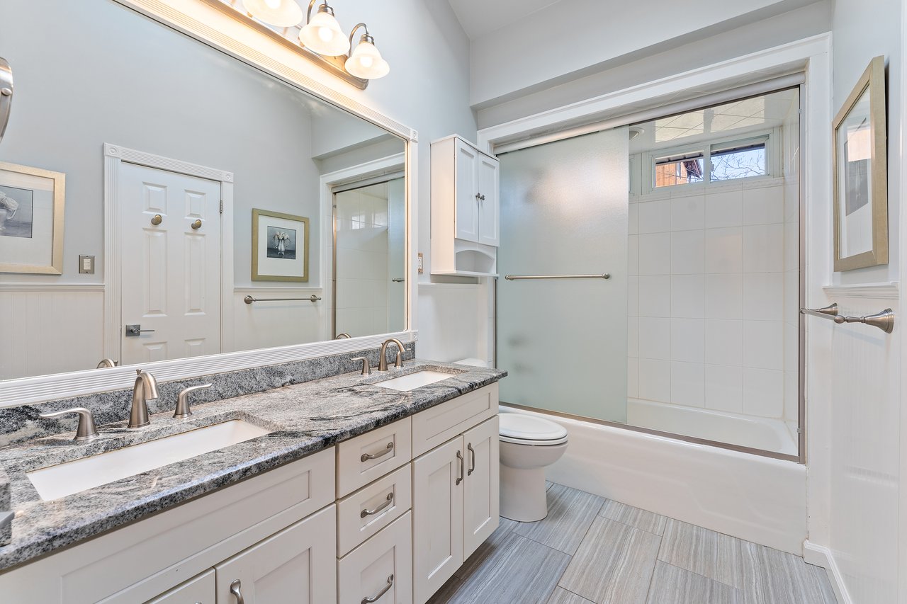 Bathroom featuring double vanity and bath / shower combo with glass door