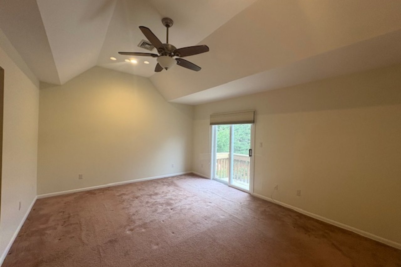 Empty room featuring carpet floors, vaulted ceiling, and ceiling fan