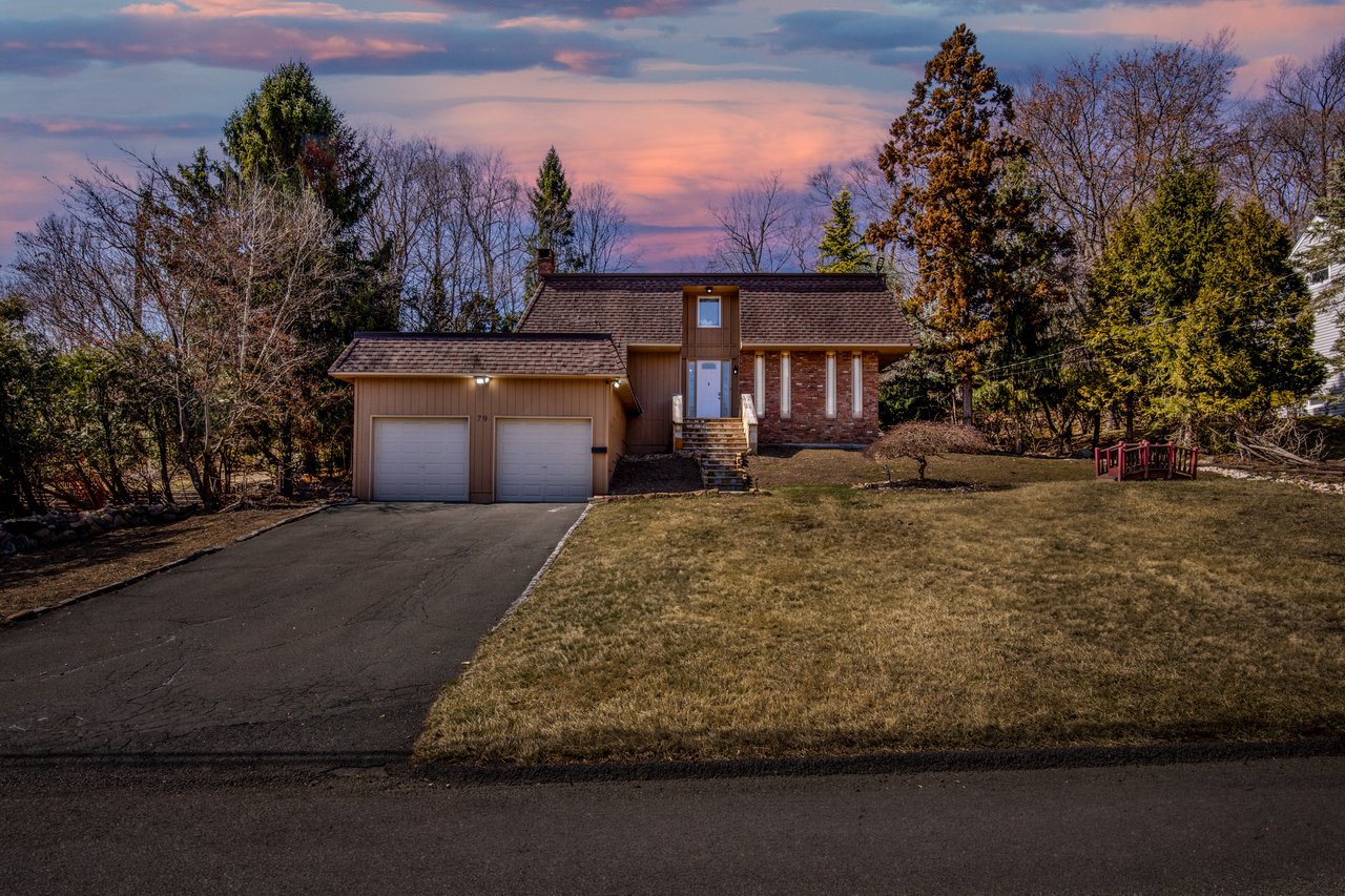 View of front of property with a shingled roof, a front lawn, asphalt driveway, mansard roof, and an attached garage
