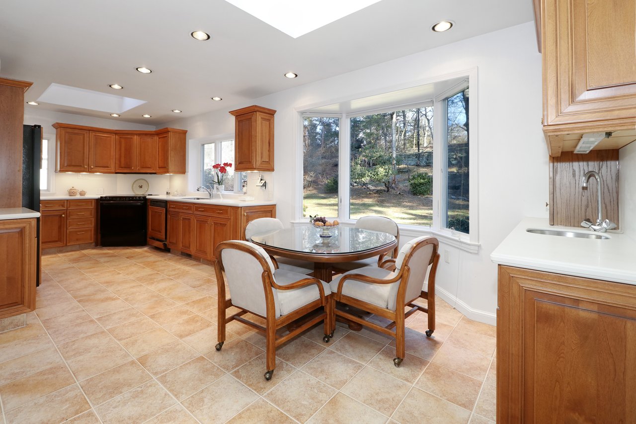 Large eat-in-kitchen with wet bar and dining nook with bay window overlooking rear grounds.