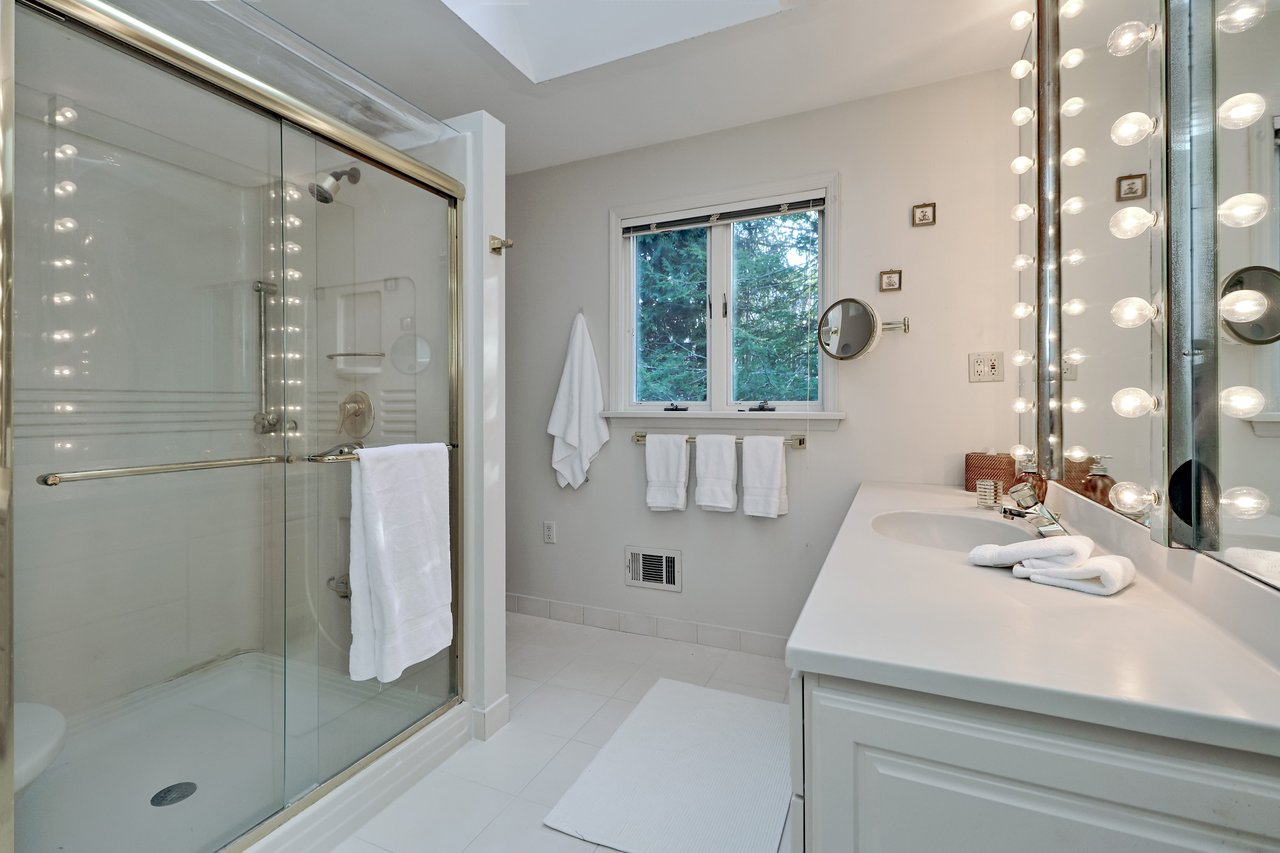 Sunny, full bath in primary suits boasts skylights, large shower with seat and tile floor.