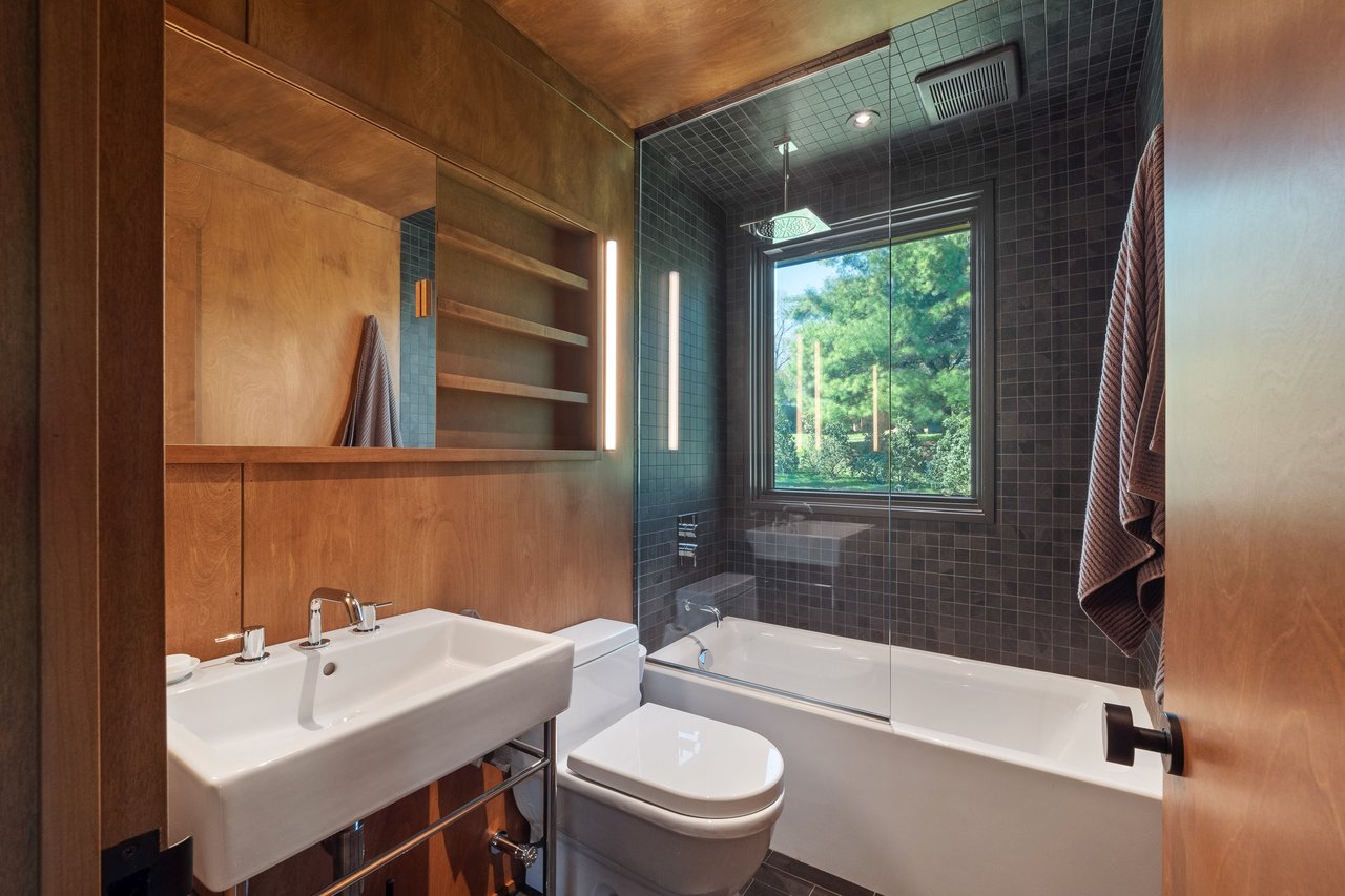 Bathroom featuring combined bath / shower with glass door and toilet
