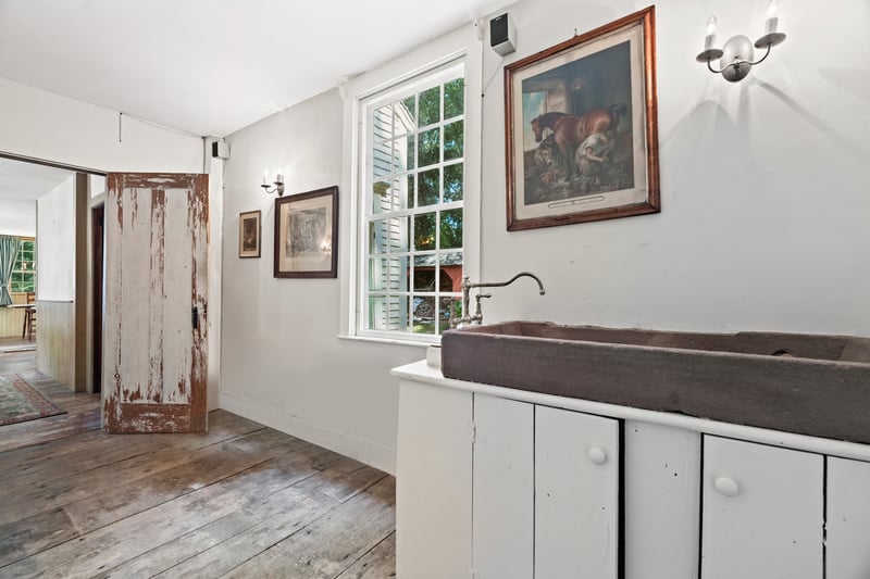 With additional, convenient access from the side entrance of the house, the service room augments the dining room and kitchen which is beyond the handsome, distressed antique door.