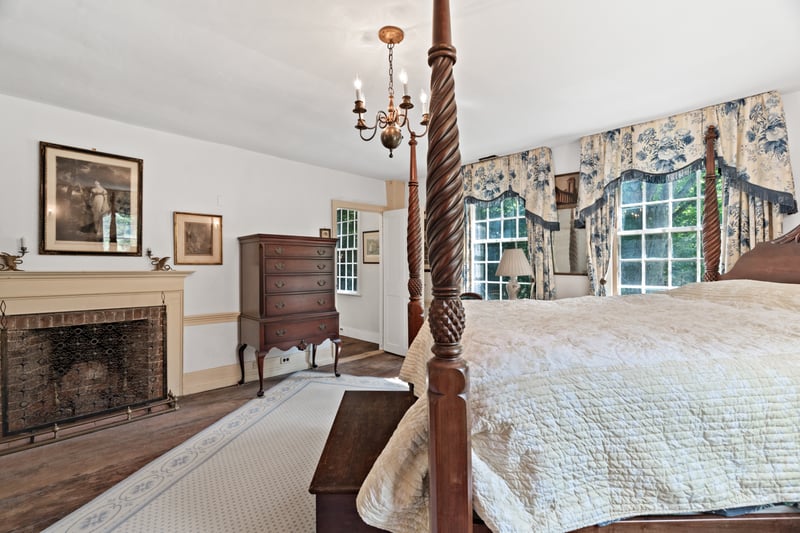 The primary bedroom sleeping space with fireplace is adorned with period features.