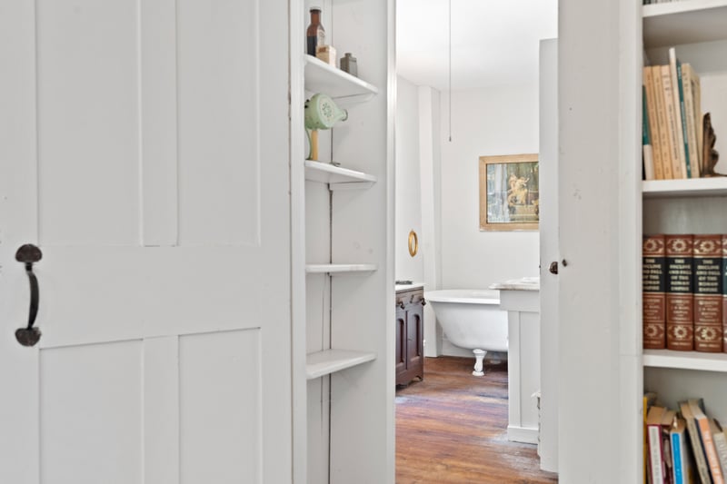 Enjoy a peekaboo look into the primary bath from the bedroom though the period door and hardware and built-in bookcases.