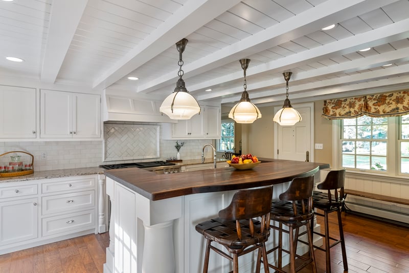 Central island and white shiplap ceiling with beams define this kitchen's crisp, coast charm