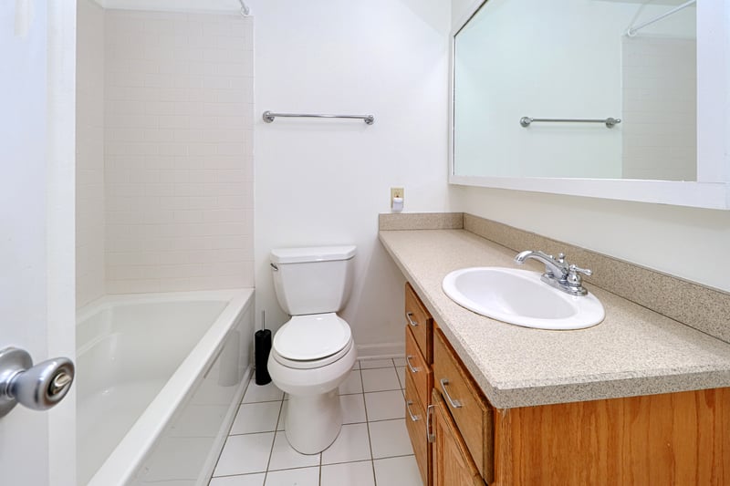The bath has a tub/shower, with shelving behind the door for storage.