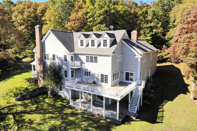 Rear view of the property. Deck overlooks a sweeping lawn.