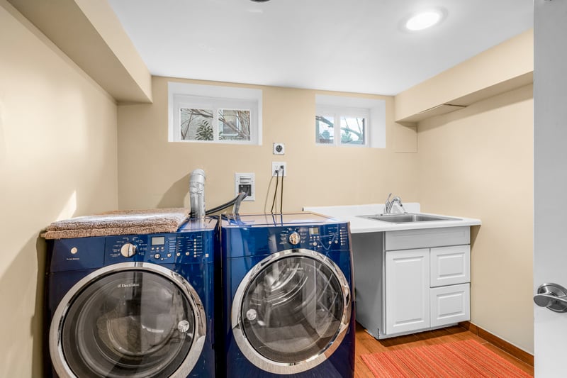 Laundry room featuring a sink, light wood-type flooring, baseboards, cabinet space, and washer and dryer