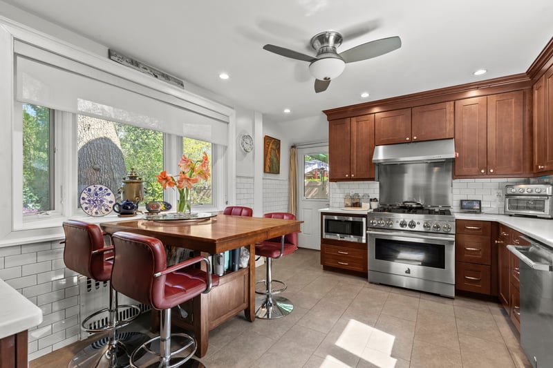 Kitchen with light countertops, decorative backsplash, stainless steel appliances and under cabinet range hood