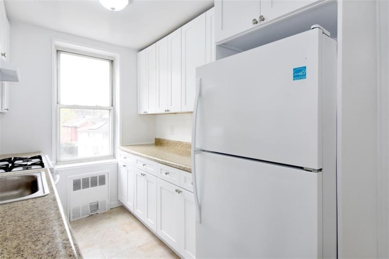 The kitchen features simple white cabinetry, matching appliances and a dishwasher....