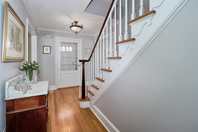 Foyer view in this center hall colonial with charming staircase detail.