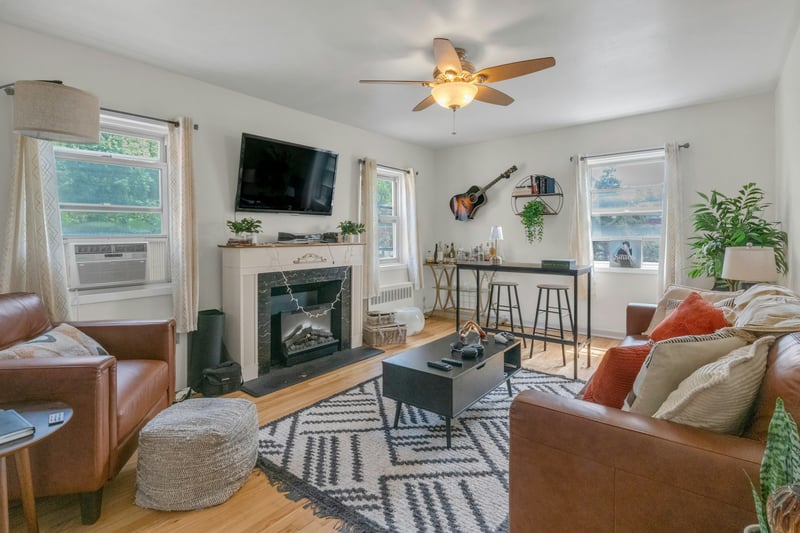 Living area featuring a fireplace, ceiling fan, plenty of natural light, and wood finished floors