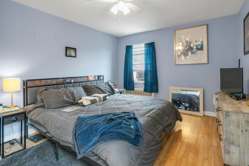 Bedroom featuring light wood-style flooring, baseboards, radiator, cooling unit, and ceiling fan