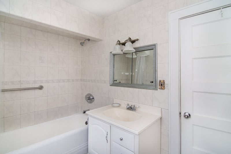 A crisp white vanity, classic tile walls, and a tub/shower combo create a clean and functional bathroom space....