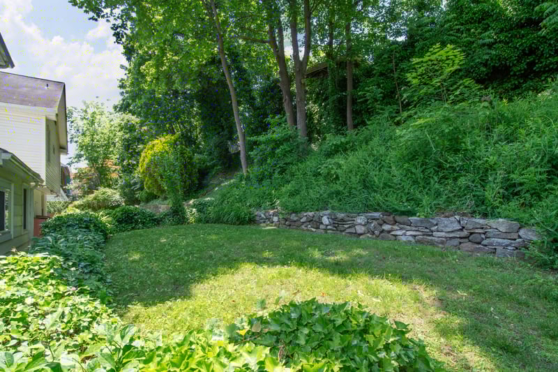 A serene, bi-level backyard features mature plantings and natural greenery....