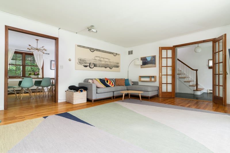 Living area featuring wood finished floors, stairway, a baseboard radiator, and french doors...
