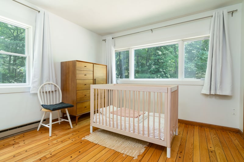Flex-room with hardwood / wood-style floors, multiple windows, a nursery area, and baseboards