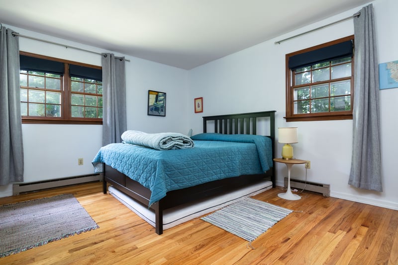 Bedroom with a baseboard radiator, multiple windows, and wood finished floors