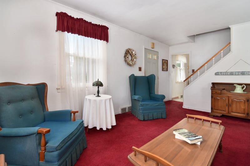 Step inside to a cozy, carpeted living room, with a staircase leading to the second floor.
