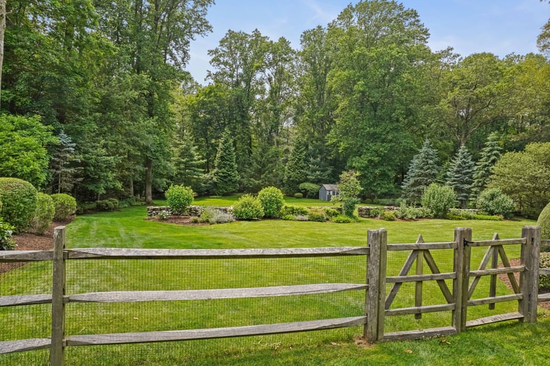 Charming accents include fencing and landscaped stone wall
