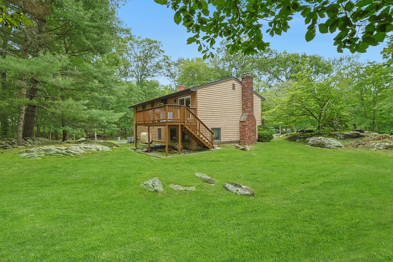Back of property featuring a chimney, stairway, a deck, and a yard