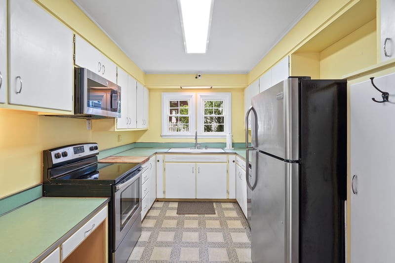 Kitchen featuring stainless steel appliances, light countertops, white cabinetry