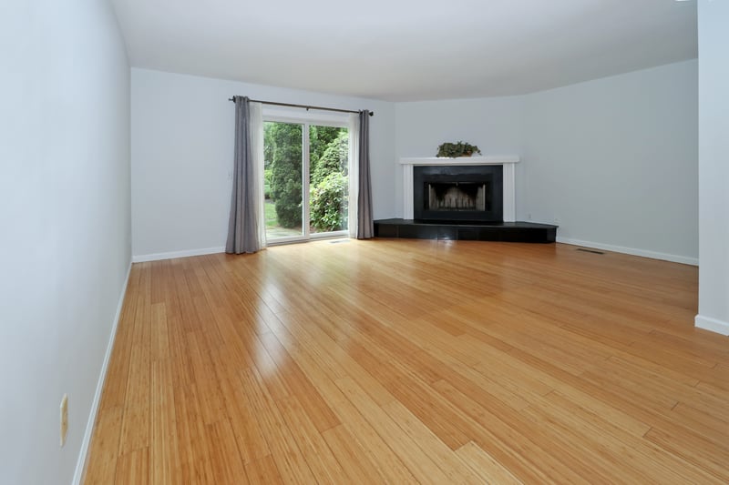View of living room with fireplace, hardwood floor and sliders which lead to patio.