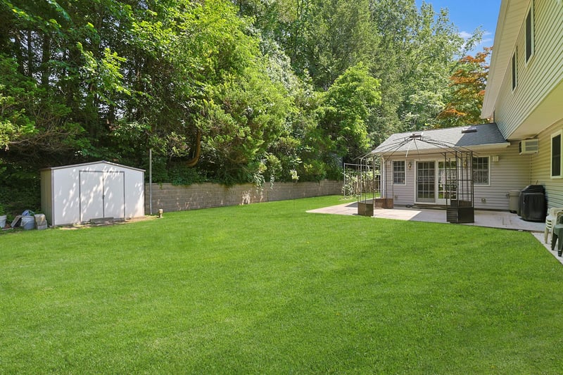 Fenced backyard featuring a patio area, a shed, and an AC wall unit