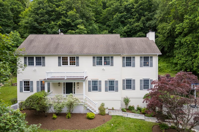 Colonial house featuring a chimney, a front yard, covered porch, and a shingled roof