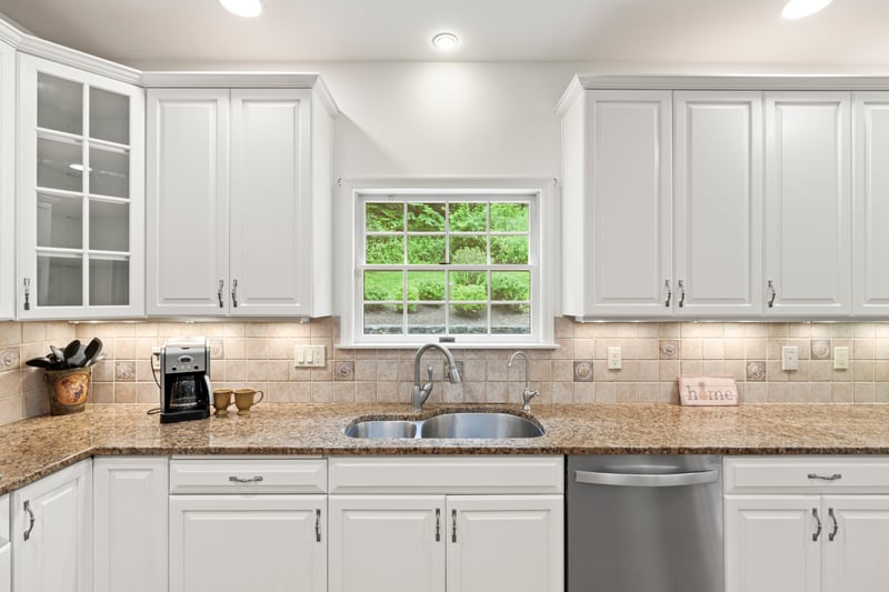 Kitchen with stainless steel dishwasher, white cabinets, glass insert cabinets, and recessed lightin