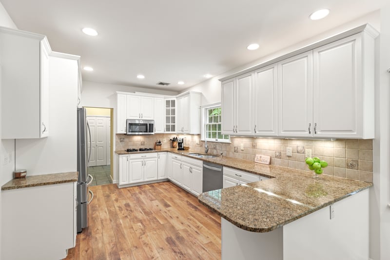 Kitchen with stainless steel appliances, a peninsula, white cabinets, stone counters, and recessed lighting