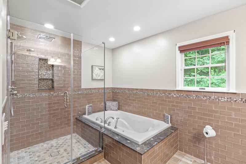 Recently Updated bathroom with a garden tub, a stall shower, tile walls, recessed lighting, and wainscoting