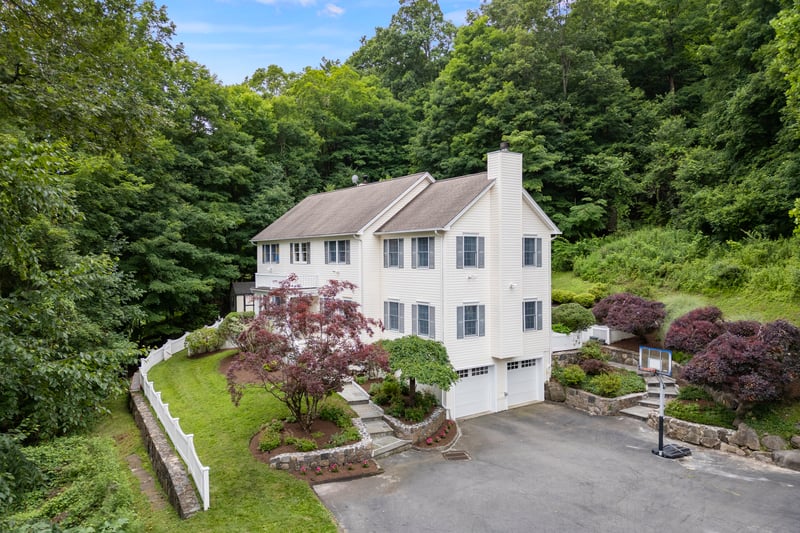 View of front of home featuring a beautiful walkway, stonewalls , mature plantings and greenery