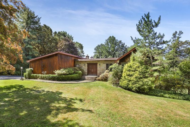 Mid-century modern home with a front lawn and wood and stone siding